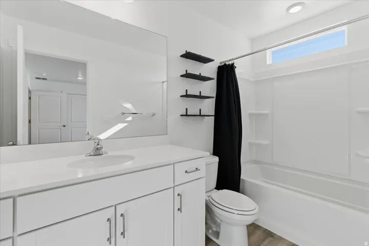 Full bath featuring shower / bathtub combination with curtain, vanity, and light wood-type flooring