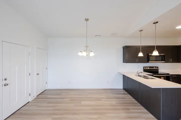 Modern kitchen featuring dark wood-finish cabinetry, light countertops, and stainless steel appliances