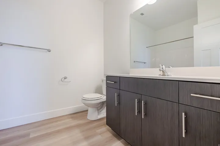 Bathroom featuring a dark wood-finish vanity with ample storage, a white countertop, and a large wall-mounted mirror