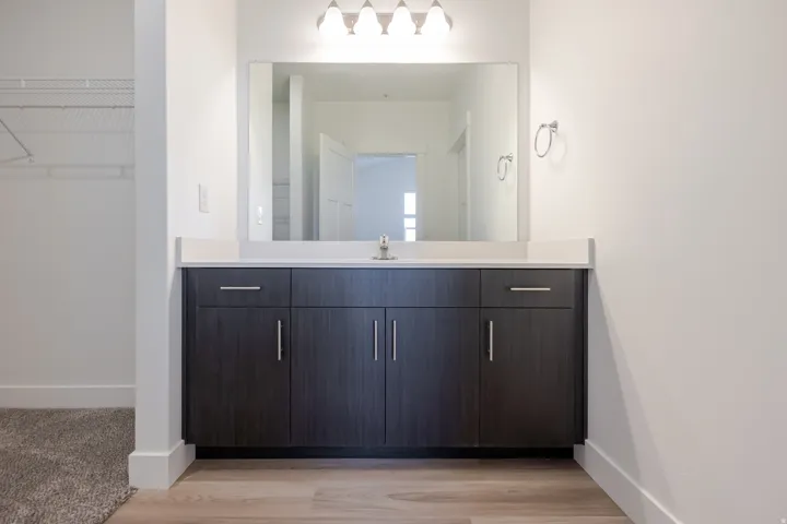 Vanity with a light-toned countertop, dark wood-finish cabinetry, and brushed nickel hardware