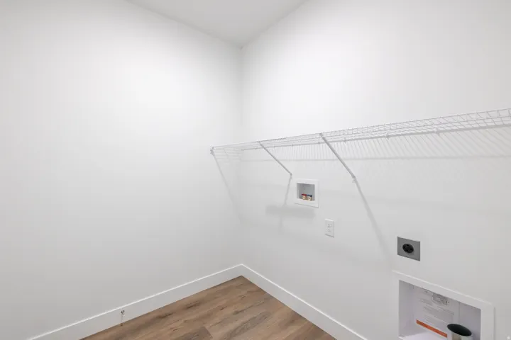 Utility space featuring wood-finish flooring, white walls, and a white wire shelf