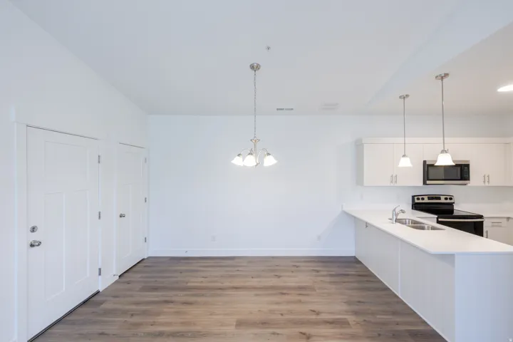 Open-concept living space featuring wood-finish flooring, white walls, and a modern kitchen