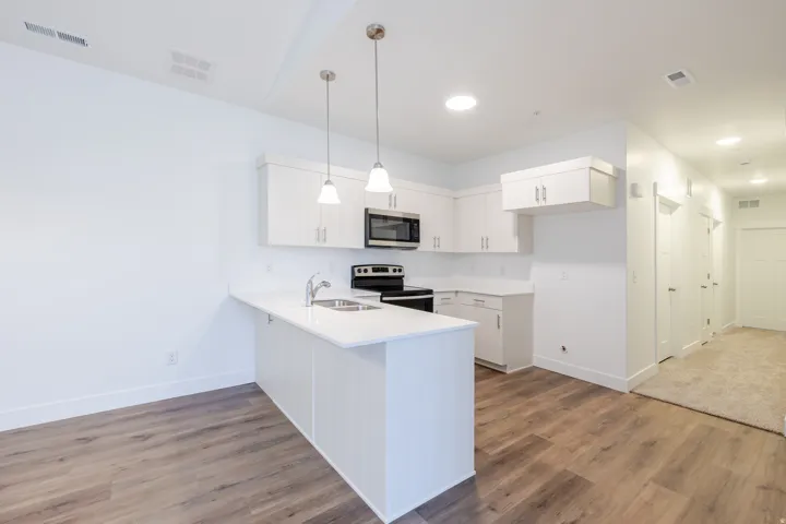 Kitchen featuring white cabinetry, stainless steel microwave, and a white countertop with an integrated sink