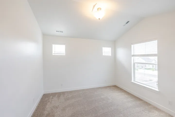 Carpeted room featuring a vaulted ceiling and white walls