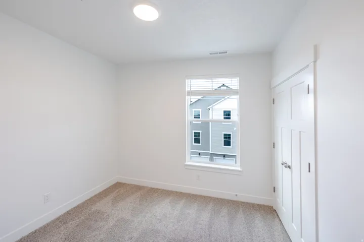 Bright interior space featuring light gray carpeting, crisp white walls, and a recessed ceiling light
