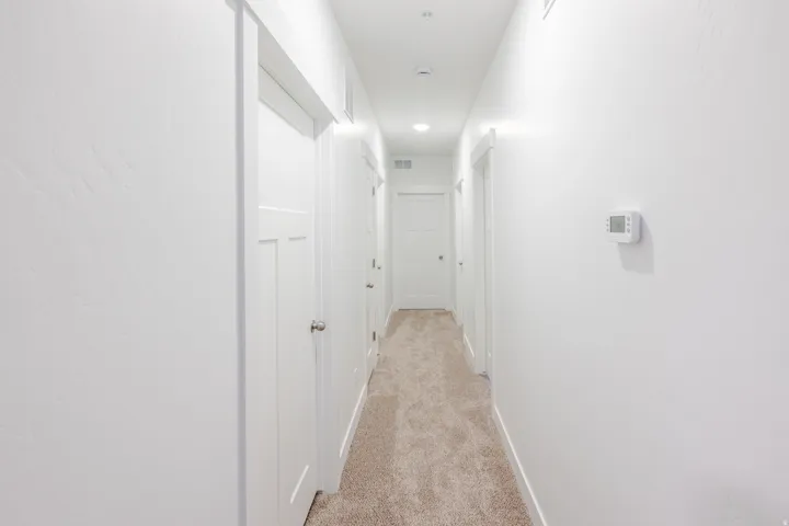 Hallway featuring light-toned carpeting, white walls, and recessed lighting