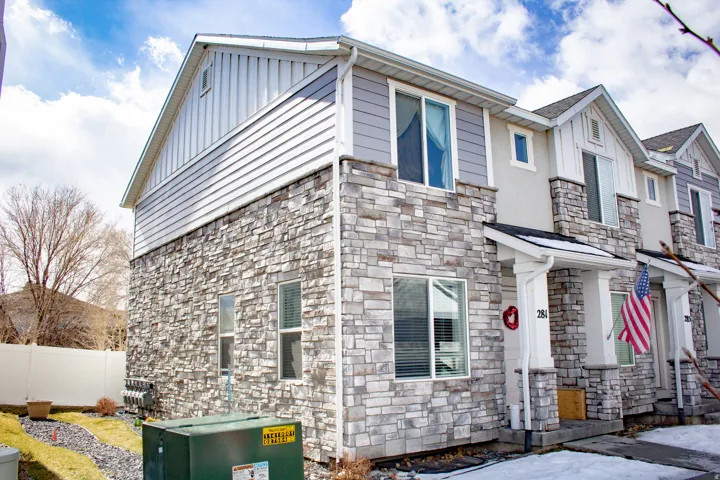 Townhome exterior featuring a stone facade and light-colored siding
