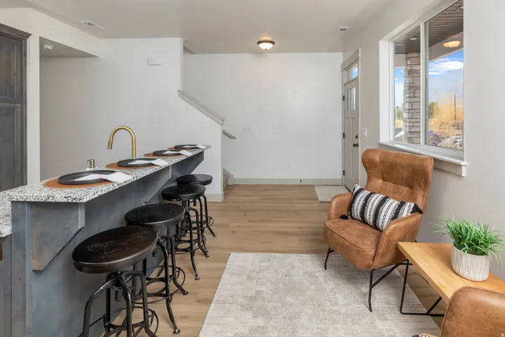 Kitchen island with granite countertop and integrated sink, wood-finish flooring, staircase, and a transom window above the entry door
