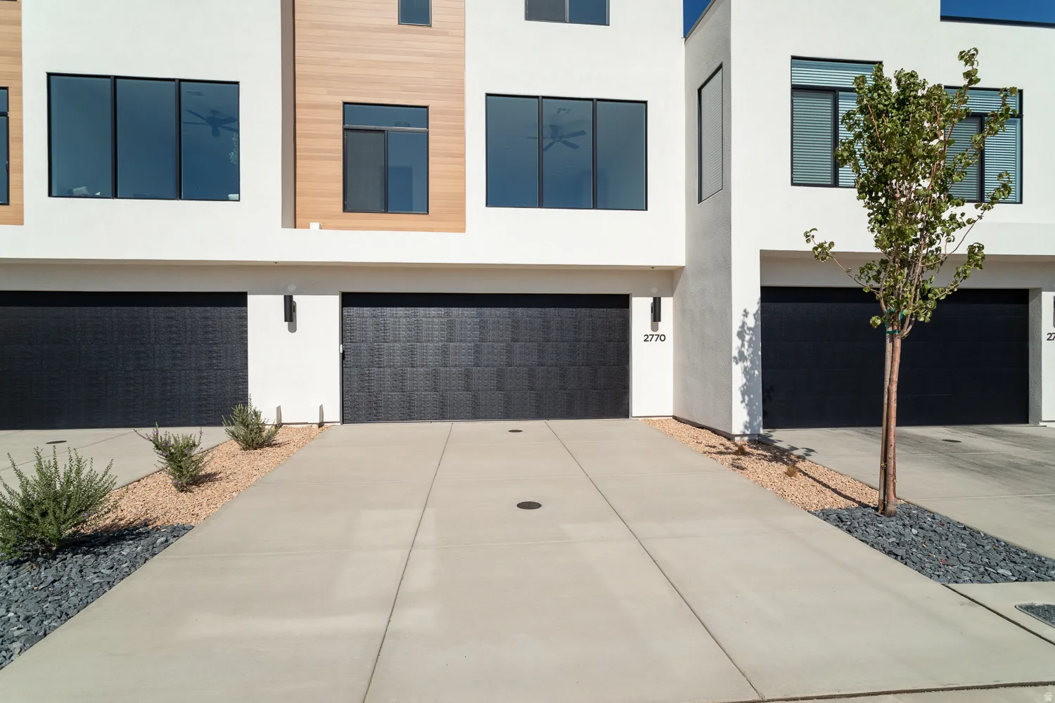 Modern home featuring a garage, concrete driveway, and stucco siding