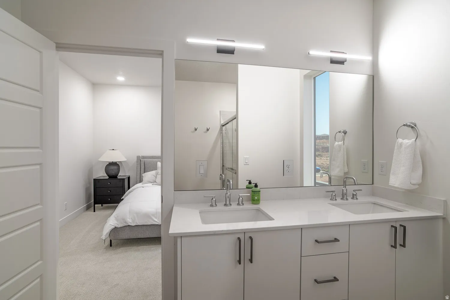 Ensuite bathroom featuring double vanity, a stall shower, light carpet, and recessed lighting