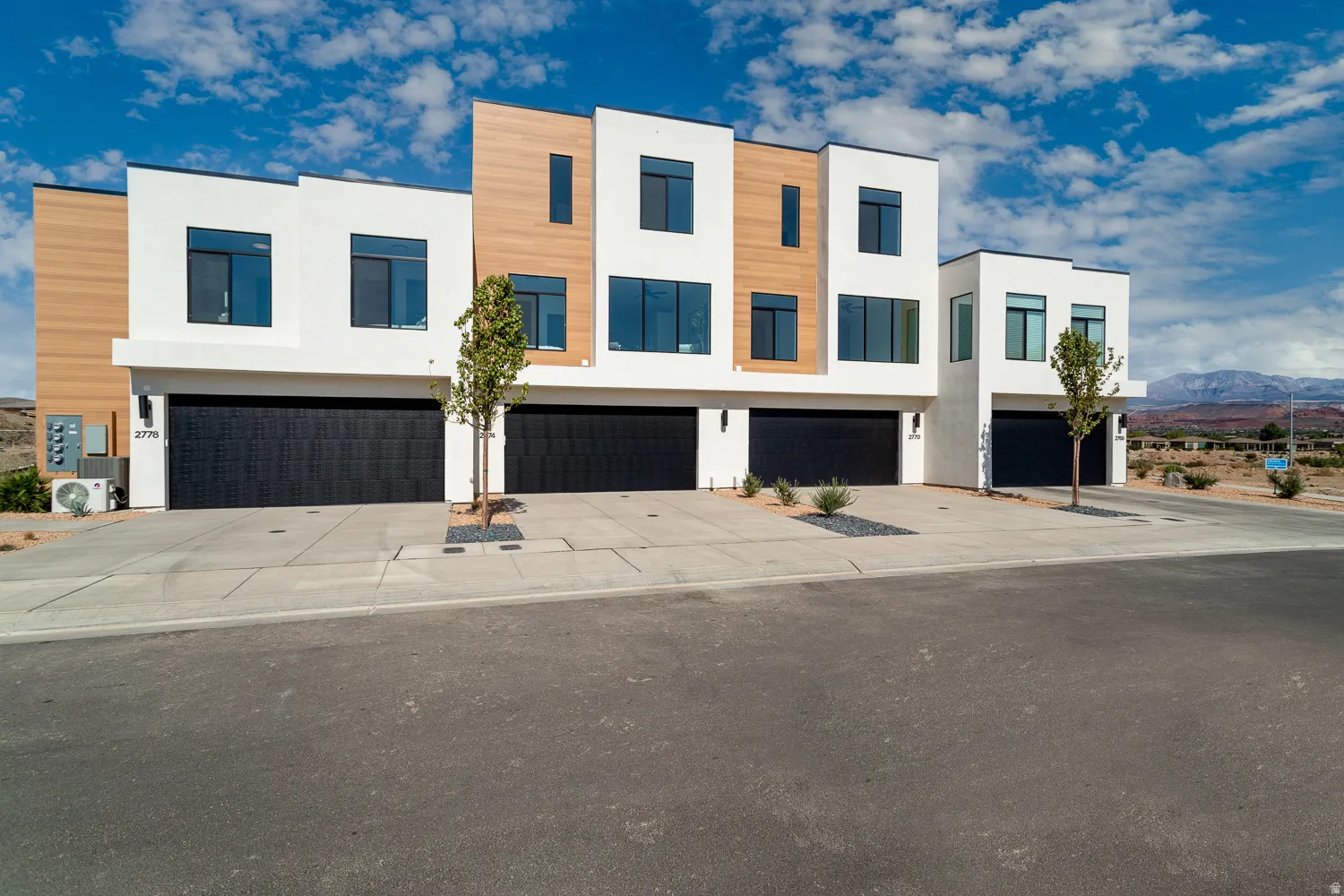 Contemporary home with stucco siding, driveway, a mountain view, and an attached garage