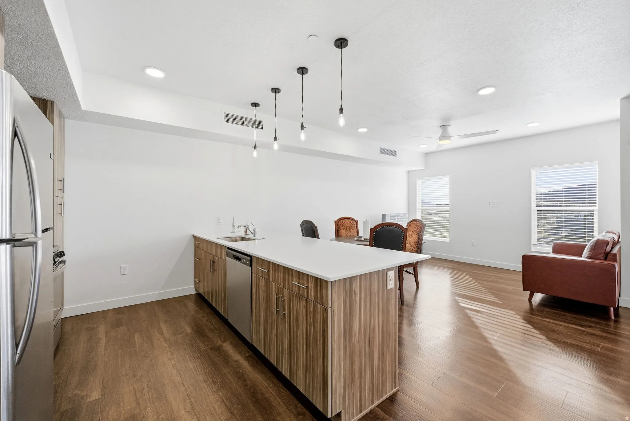 Kitchen featuring a peninsula, open floor plan, stainless steel appliances, decorative light fixtures, and dark wood-type flooring