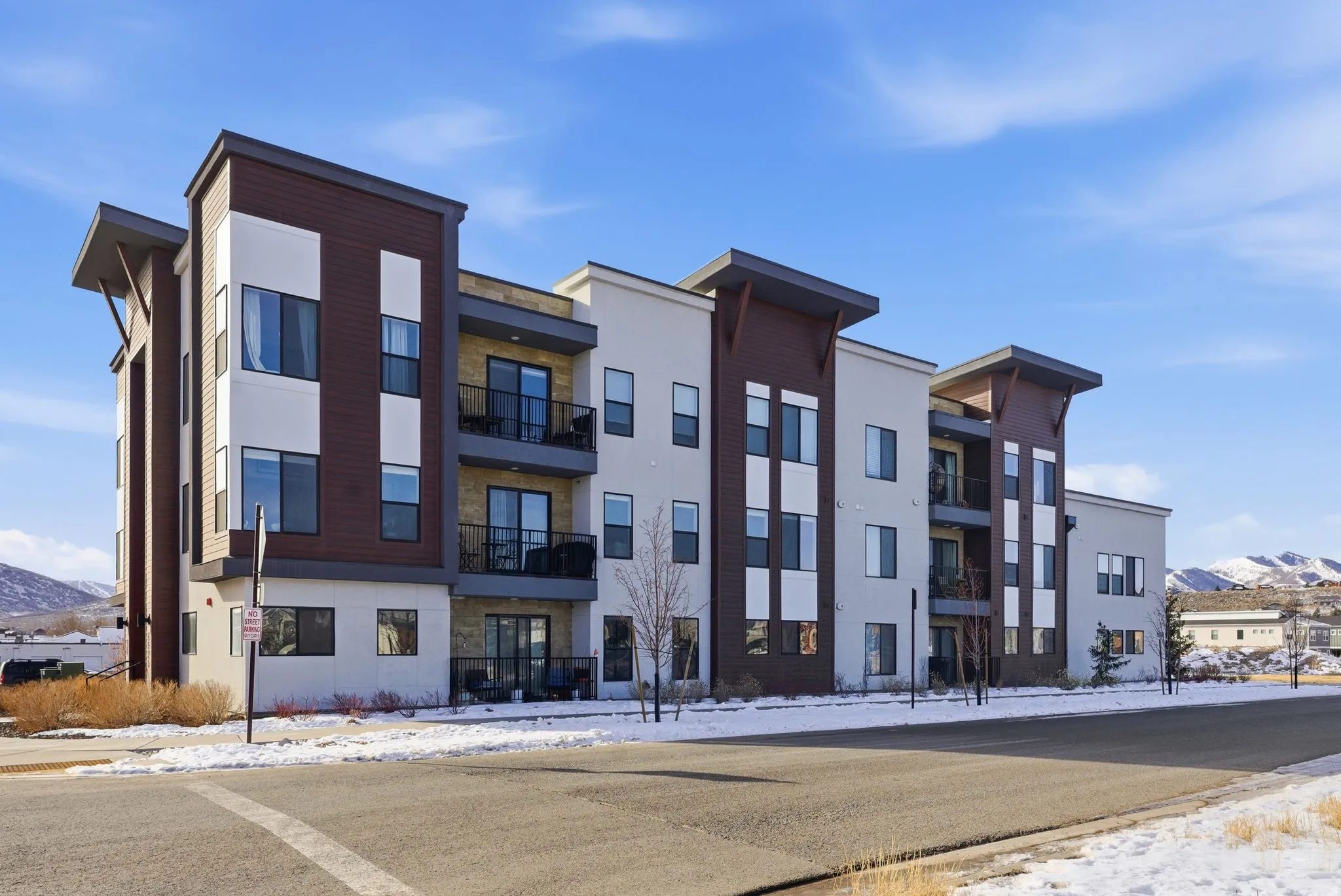 Snow covered building featuring a view of apartment building / complex and a mountain view