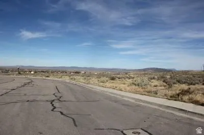 View of asphalt road featuring sidewalks, a view of countryside, and a mountain view