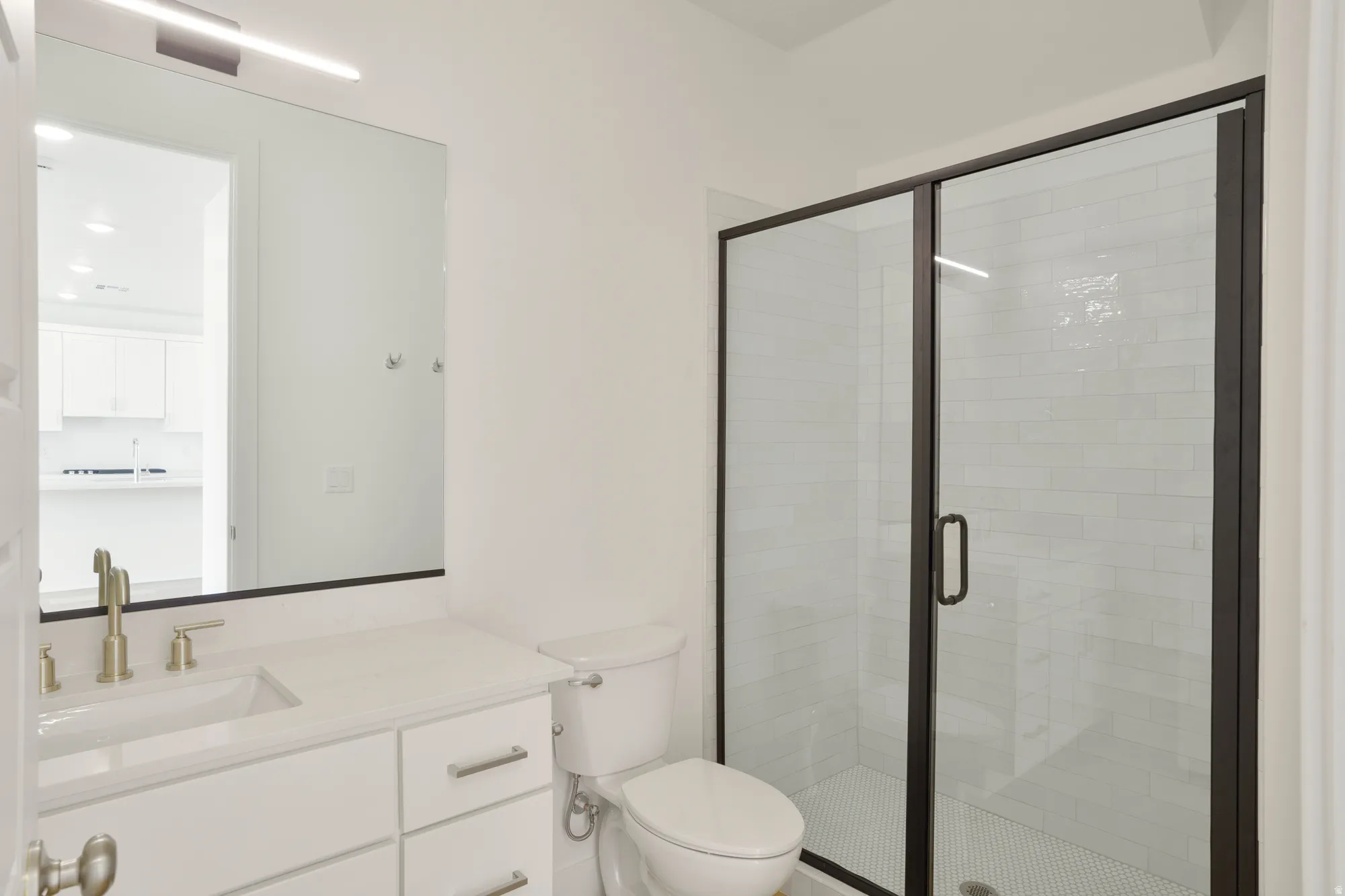 Bathroom featuring a glass-enclosed shower with black framing, white subway tile surround, and mosaic tile flooring