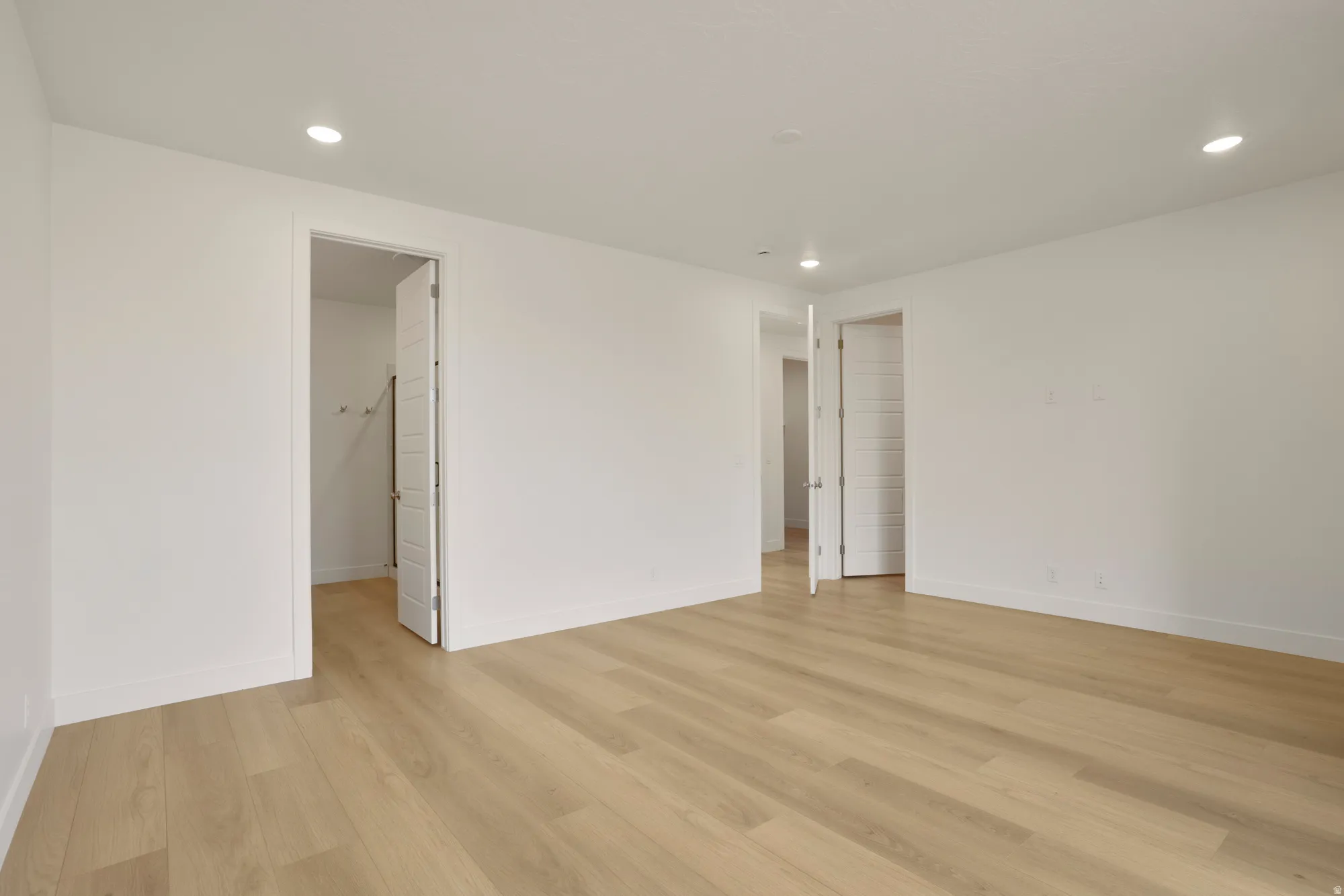 Spacious room featuring light wood-finish flooring and recessed lighting
