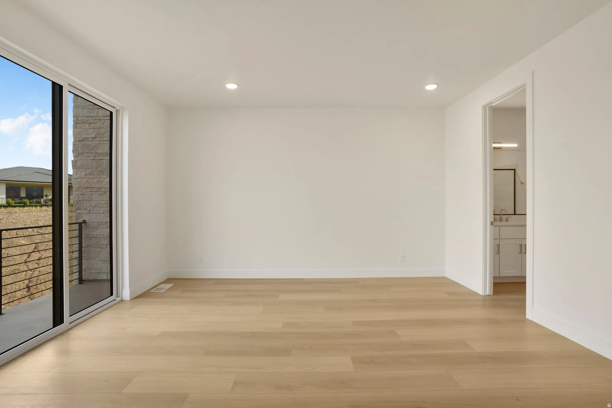 Spacious interior featuring light wood-finish flooring, recessed lighting, and white baseboards