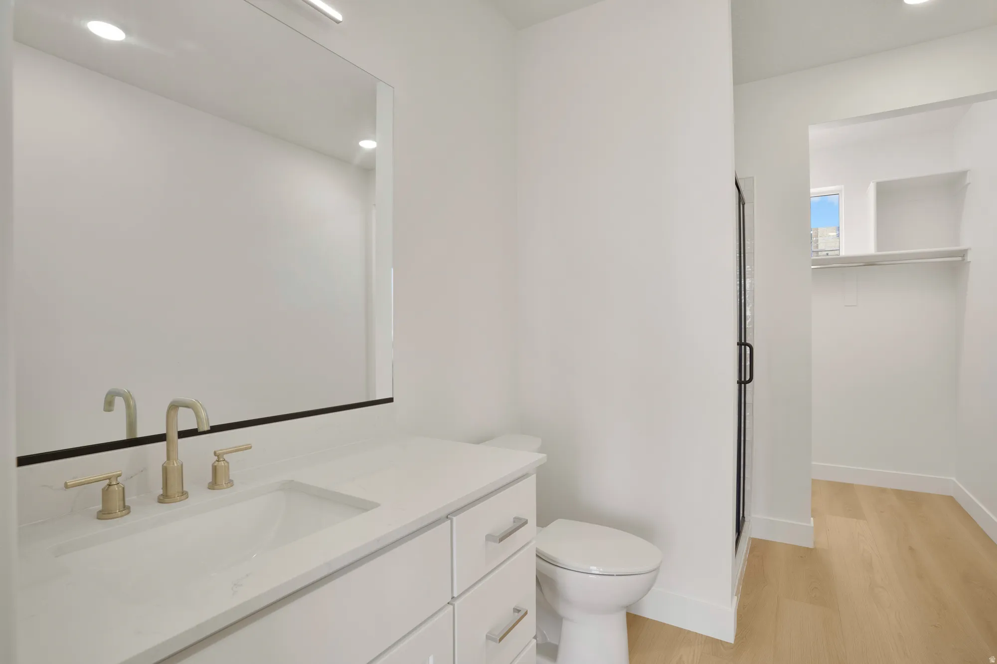 Bathroom featuring a single vanity with gold-tone fixtures, white cabinetry, and a rectangular undermount sink