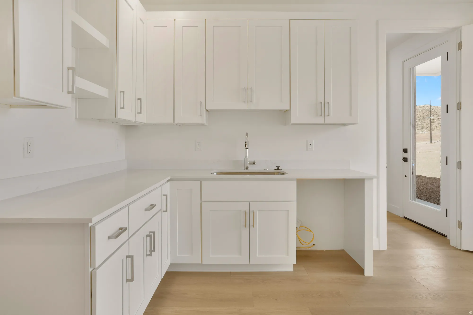Utility room featuring white shaker cabinetry, light-toned wood-finish flooring, and light countertops