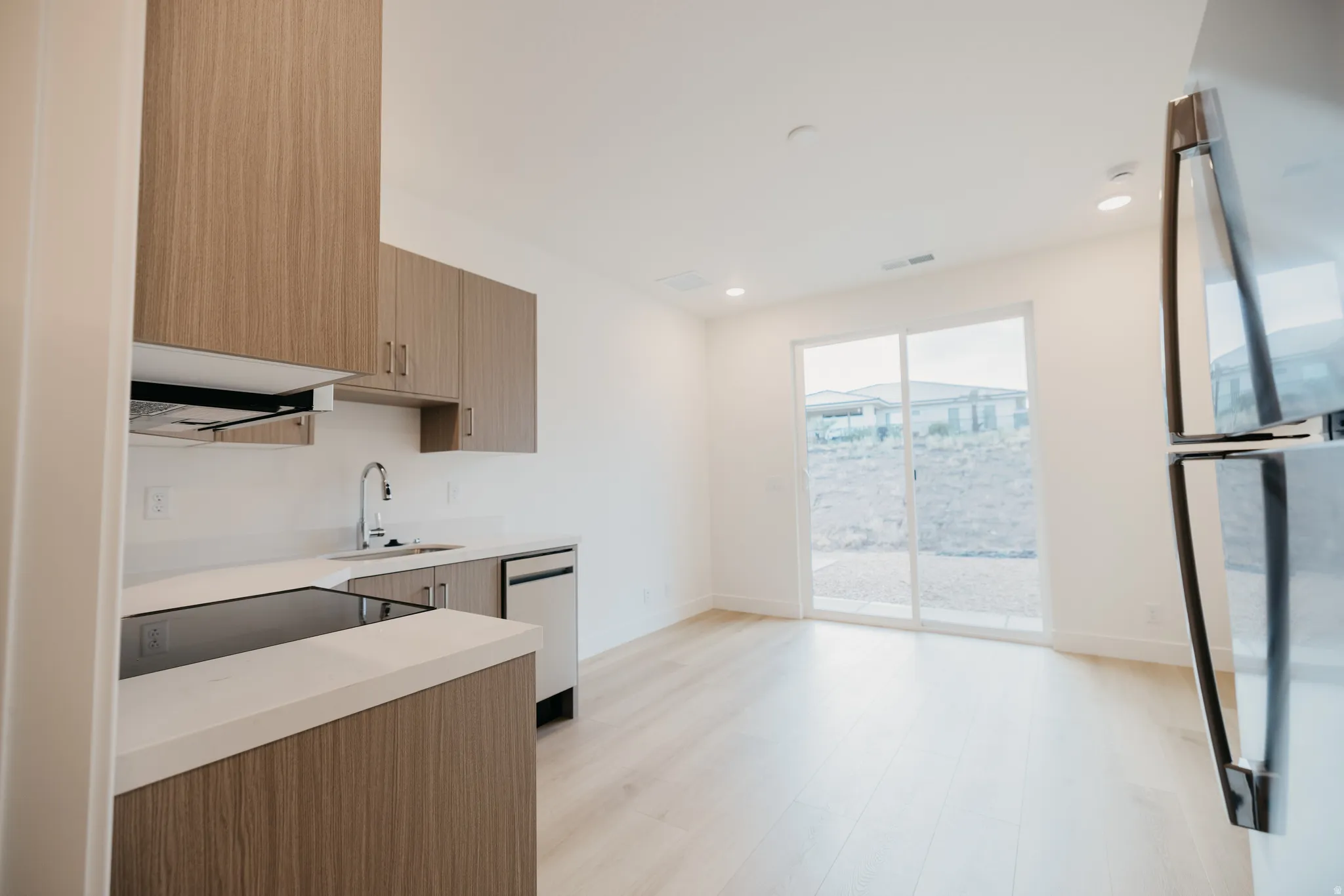 Kitchen with modern cabinets, appliances with stainless steel finishes, recessed lighting, light wood finished floors, and brown cabinetry