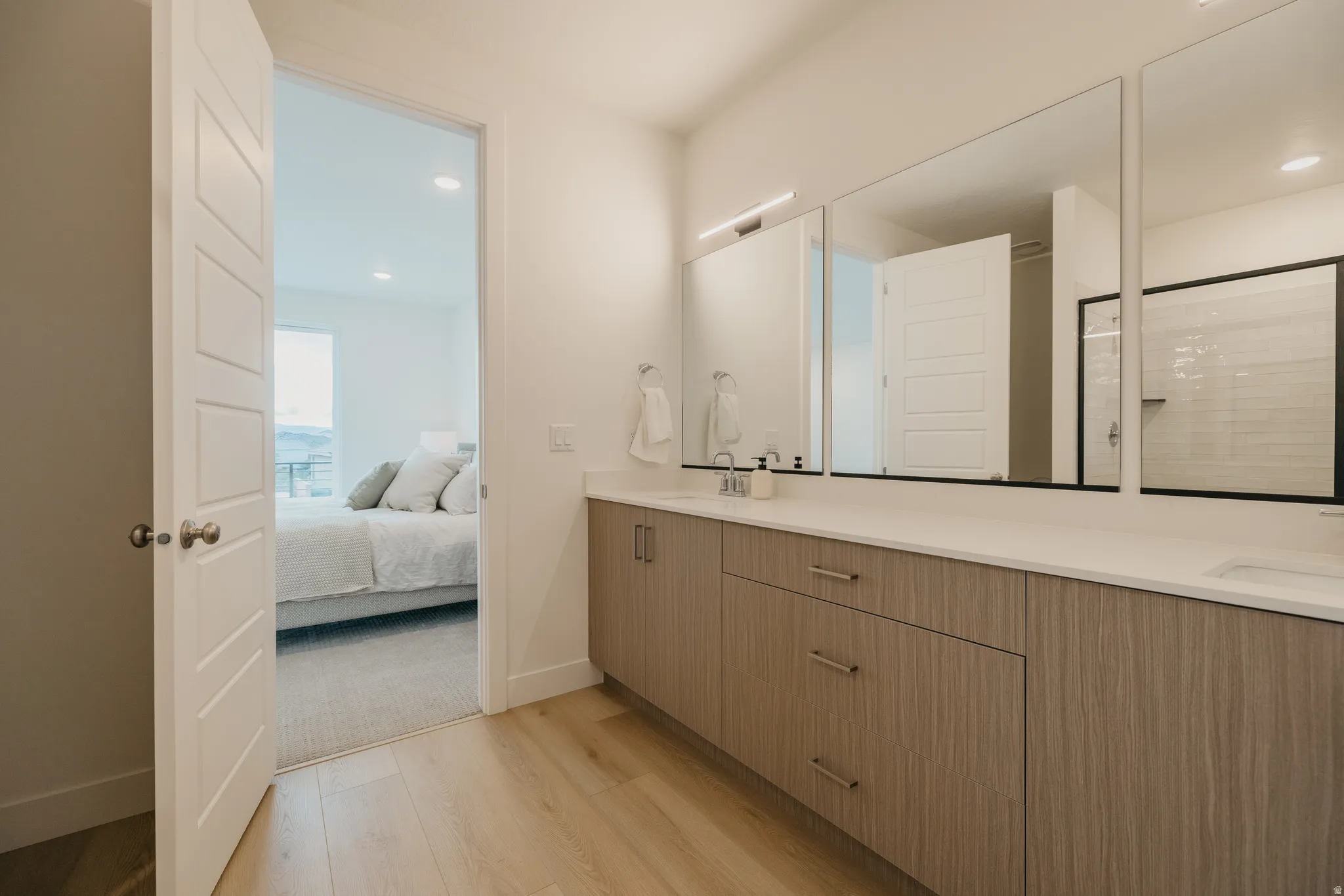 Bathroom with double vanity, light wood finished floors, connected bathroom, a shower with door, and recessed lighting