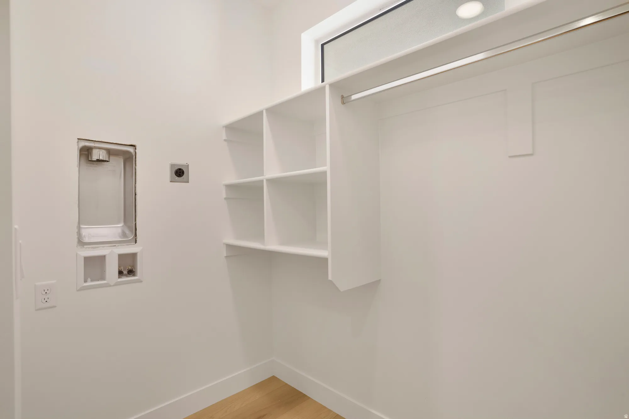 Dedicated laundry area featuring a washer hookup, dryer vent, and light wood-finish flooring