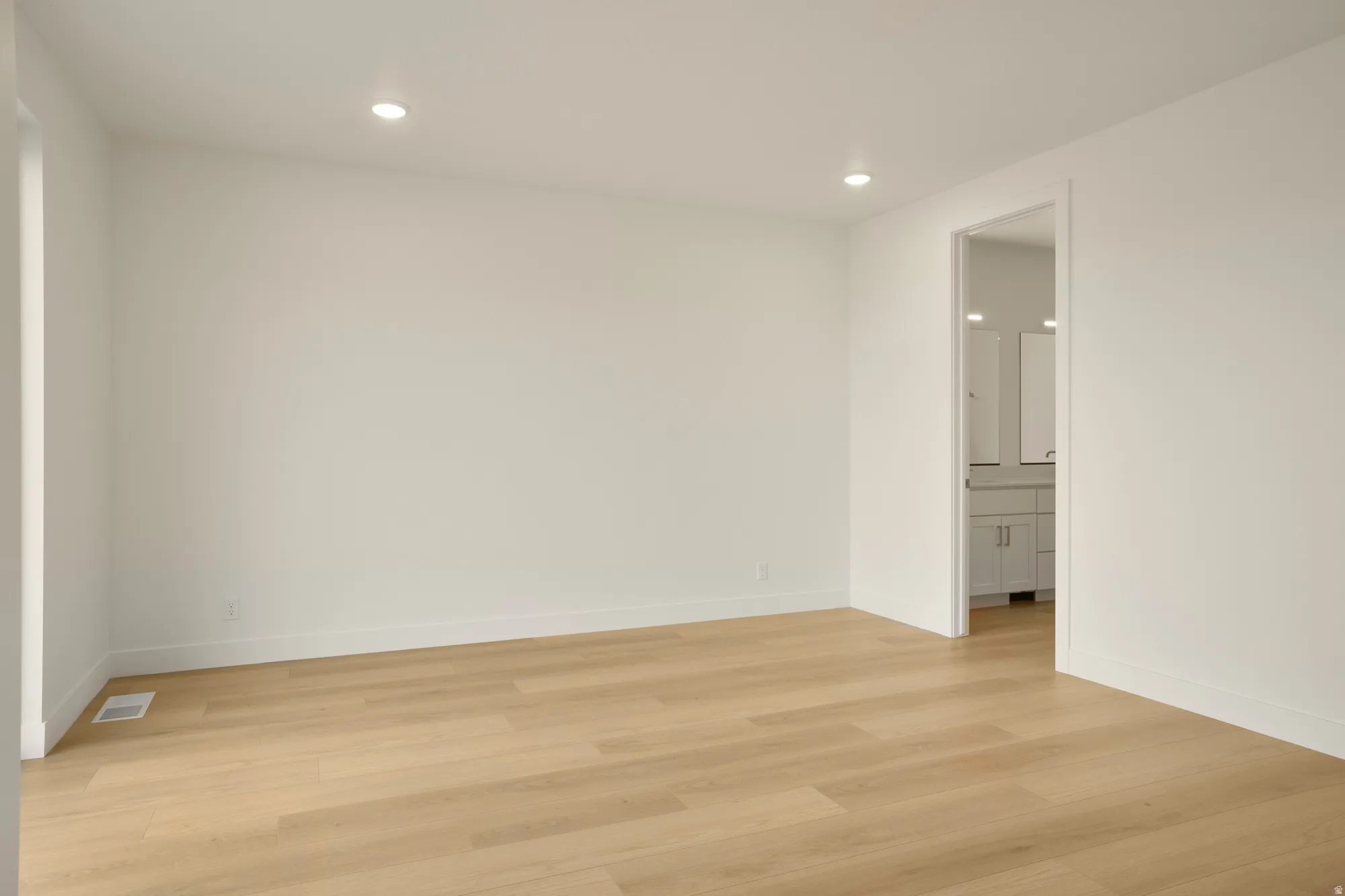Spacious room with wood-finish flooring, recessed lighting, and white baseboards