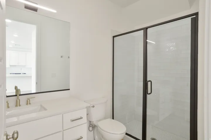 Bathroom featuring a glass-enclosed shower with black framing, white subway tile surround, and mosaic tile flooring
