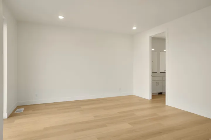 Spacious room with wood-finish flooring, recessed lighting, and white baseboards