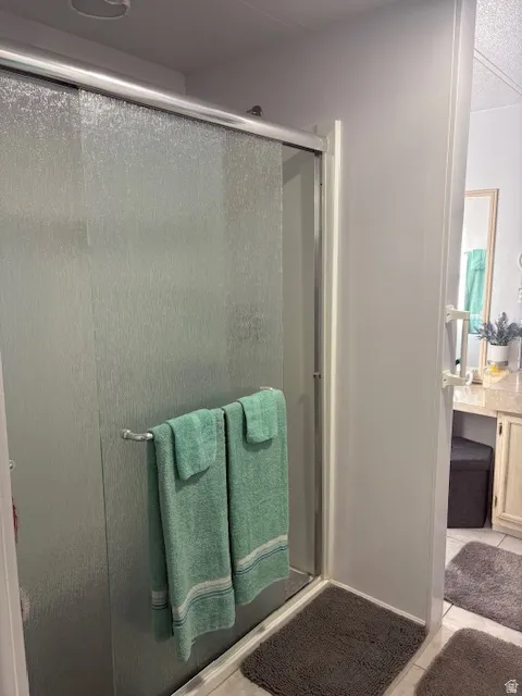 Bathroom featuring a stall shower, vanity, light tile patterned floors, and a textured ceiling