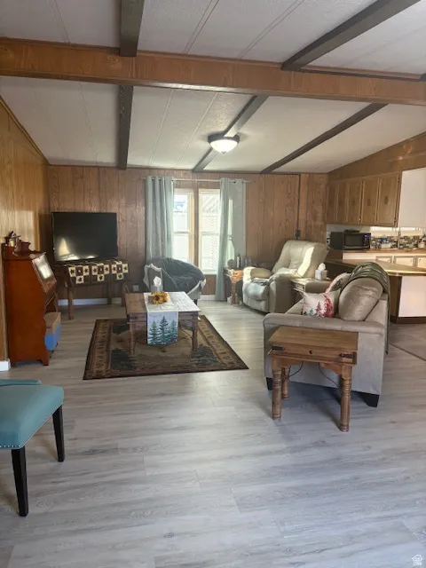 Living area with wooden walls, light wood finished floors, and a textured ceiling