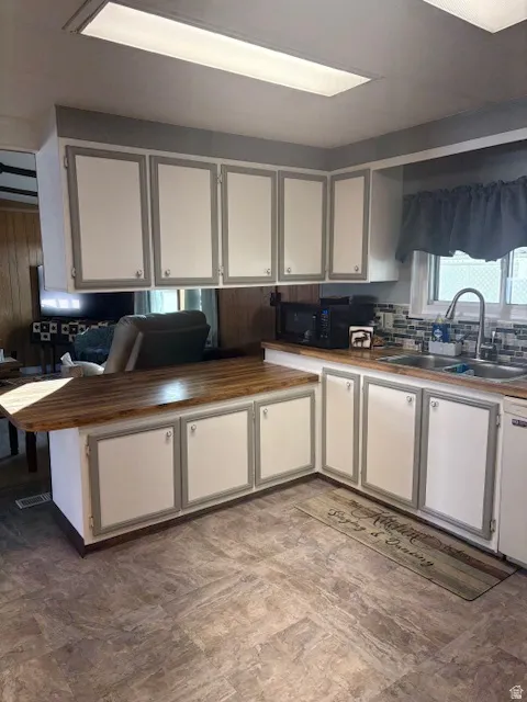 Kitchen with white cabinets, black microwave, and decorative backsplash