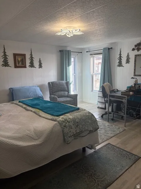 Bedroom with wood finished floors, wooden walls, and a decorative wall