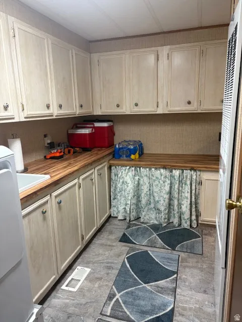 Kitchen with wooden counters, light brown cabinets, white fridge, a heating unit, and light wood-style flooring