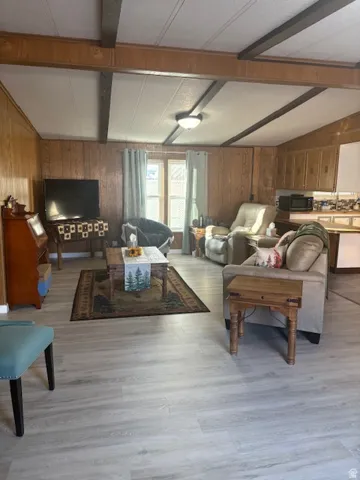 Living area with wooden walls, light wood finished floors, and a textured ceiling