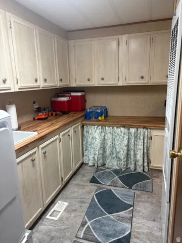 Kitchen with wooden counters, light brown cabinets, white fridge, a heating unit, and light wood-style flooring
