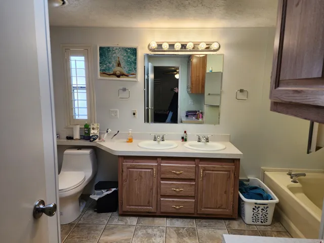 Full bath with double vanity, a bath, and a textured ceiling
