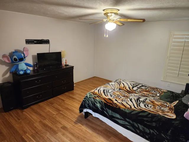 Bedroom featuring wood finished floors, a textured ceiling, and ceiling fan