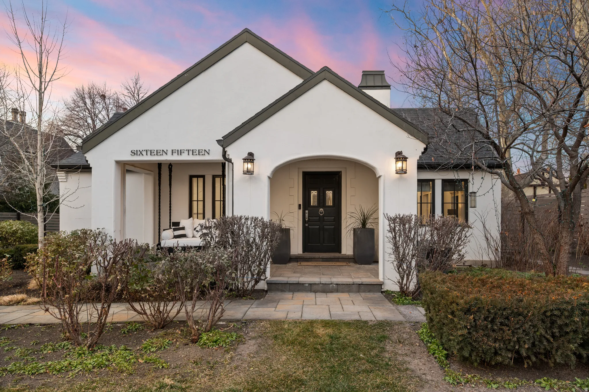 View of front of house with a porch, a chimney, and stucco siding