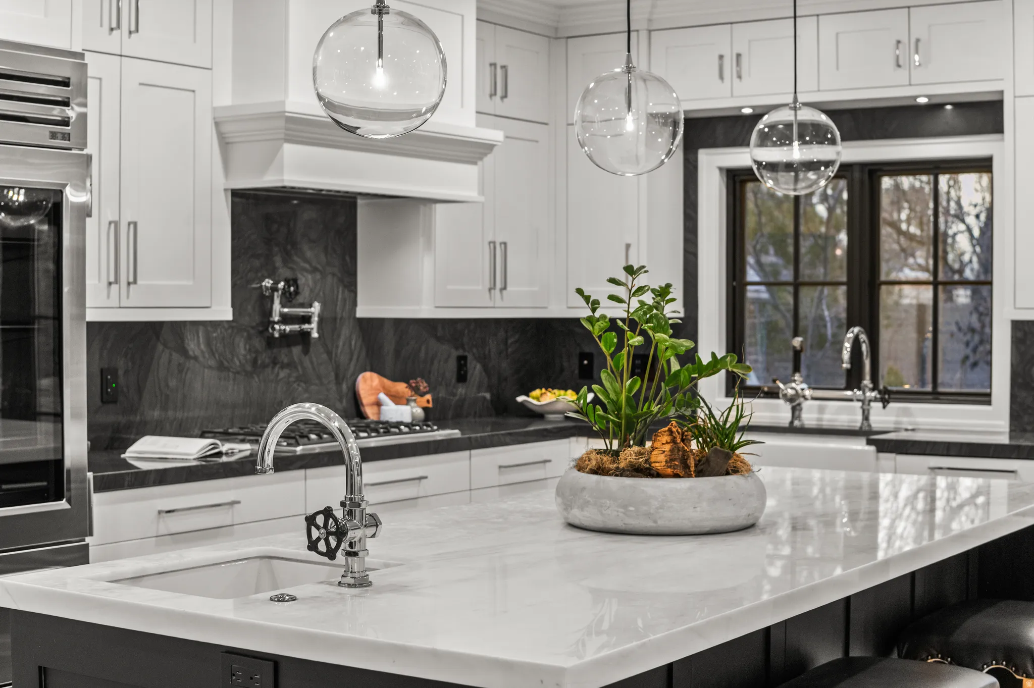 Kitchen featuring a kitchen breakfast bar, white cabinetry, dark stone counters, and an island with sink
