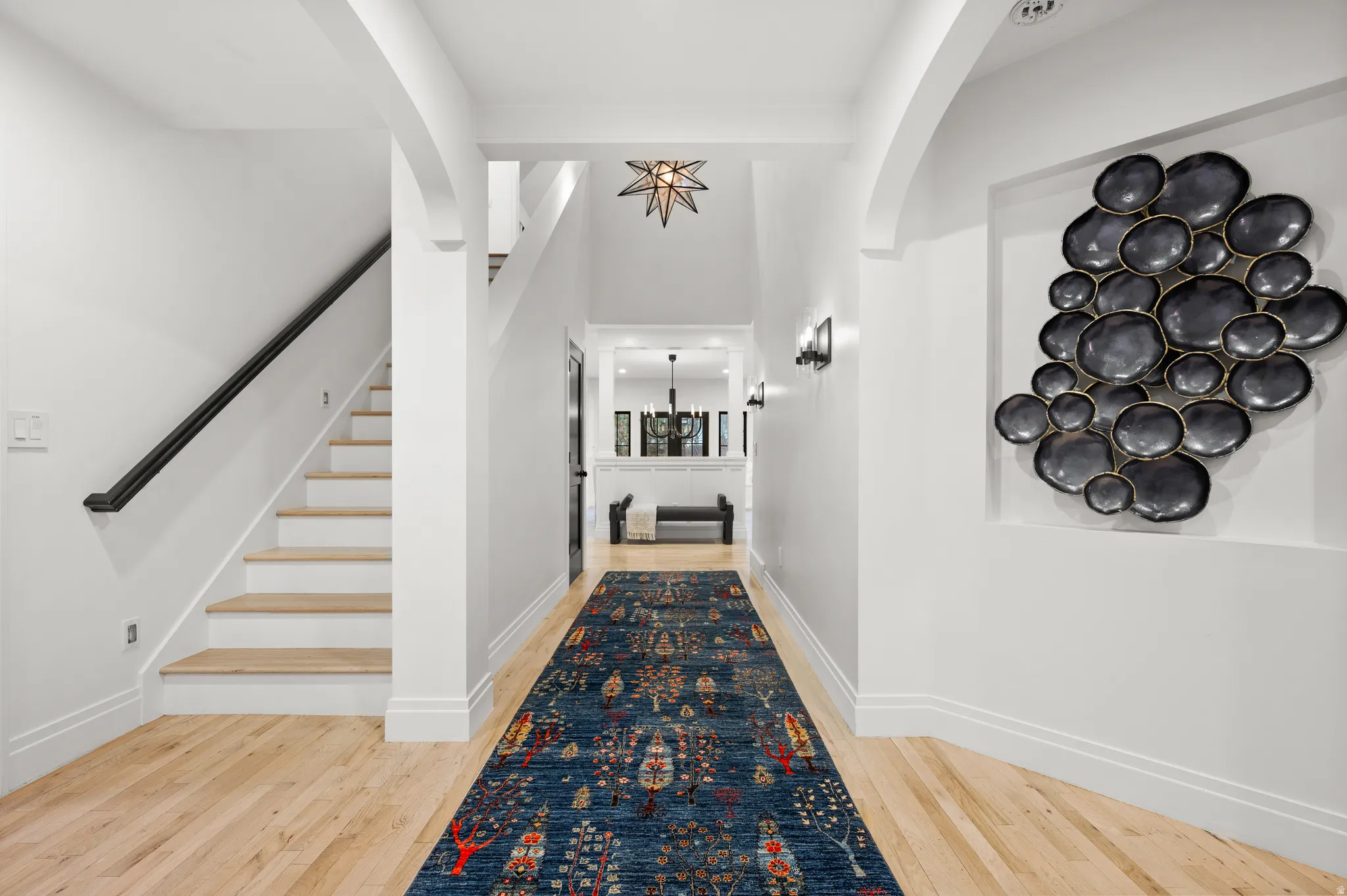 Corridor featuring light wood-style flooring, stairs, and a chandelier