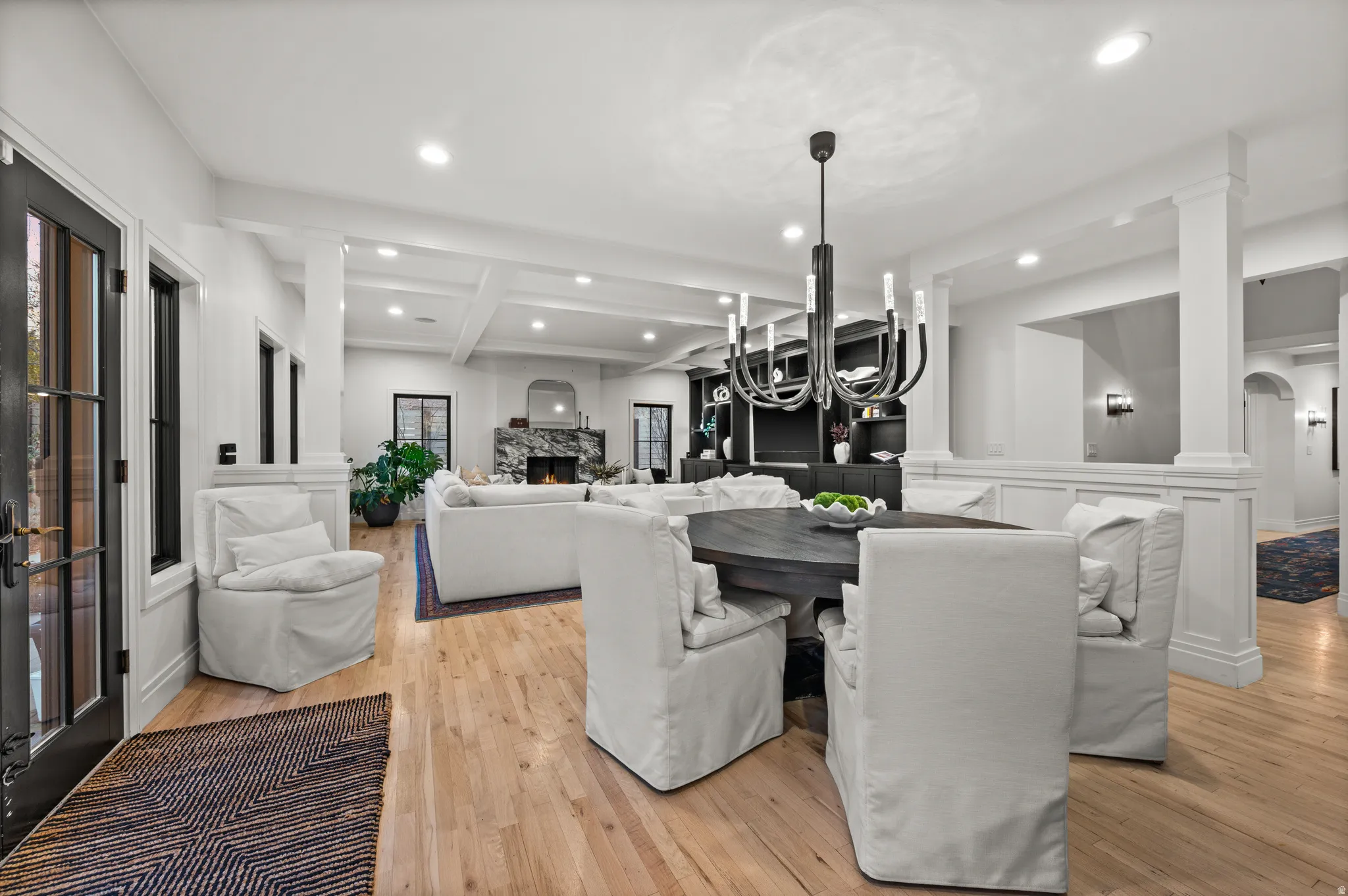 Dining area with recessed lighting, decorative columns, light wood-type flooring, beam ceiling, and a fireplace