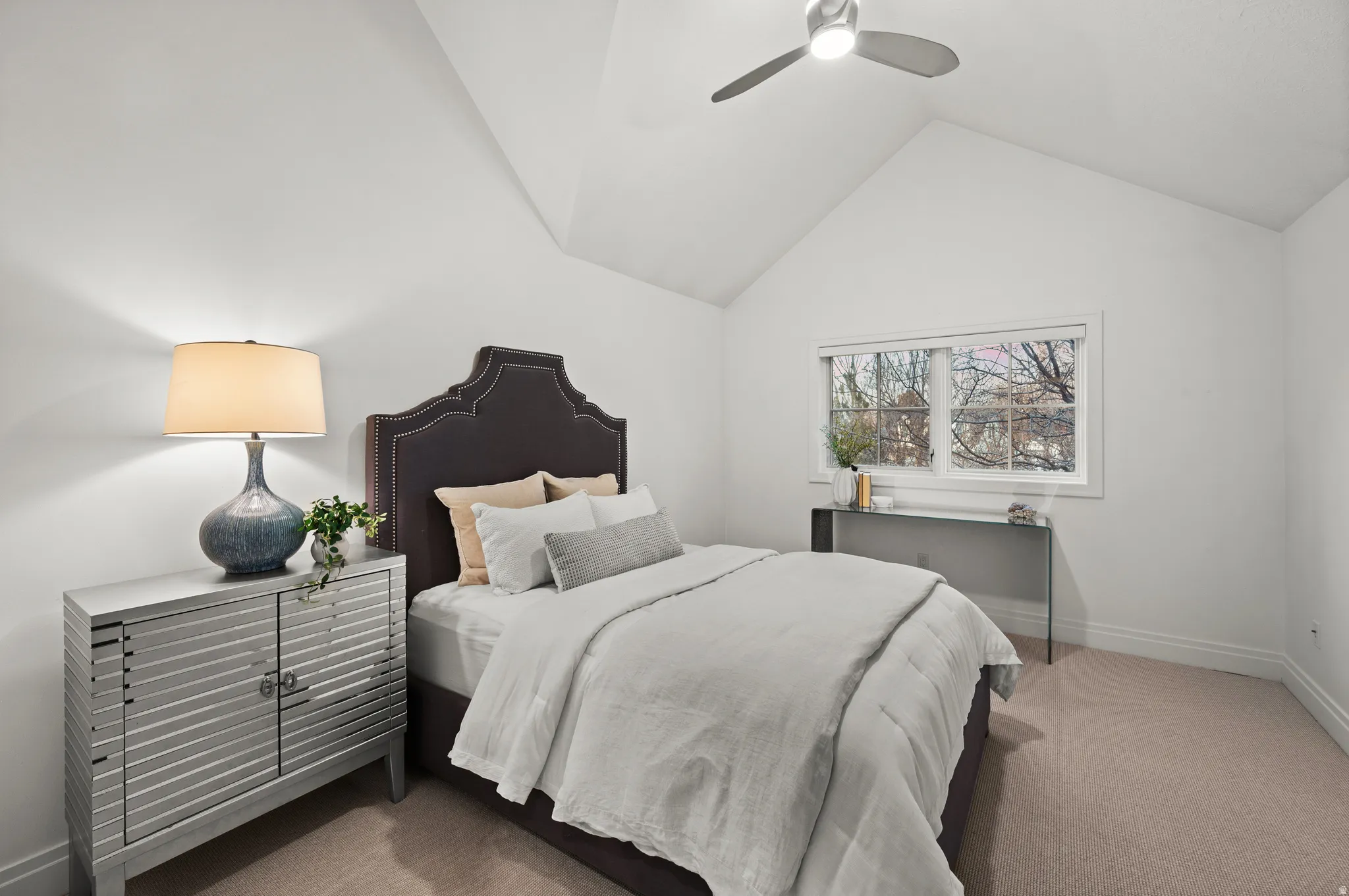 Carpeted bedroom with ceiling fan and lofted ceiling