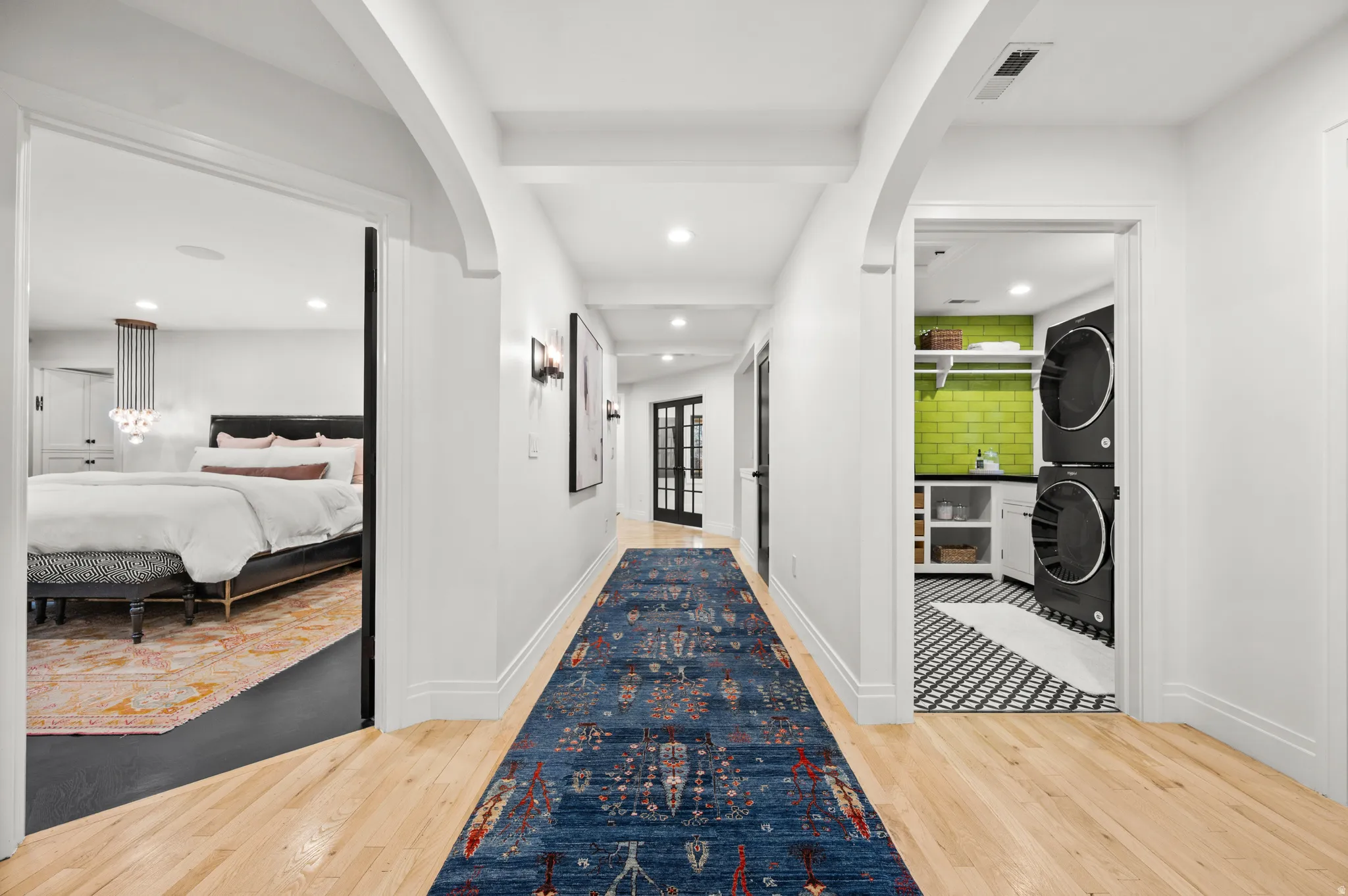 Corridor with light wood-type flooring, arched walkways, recessed lighting, and stacked washer and clothes dryer