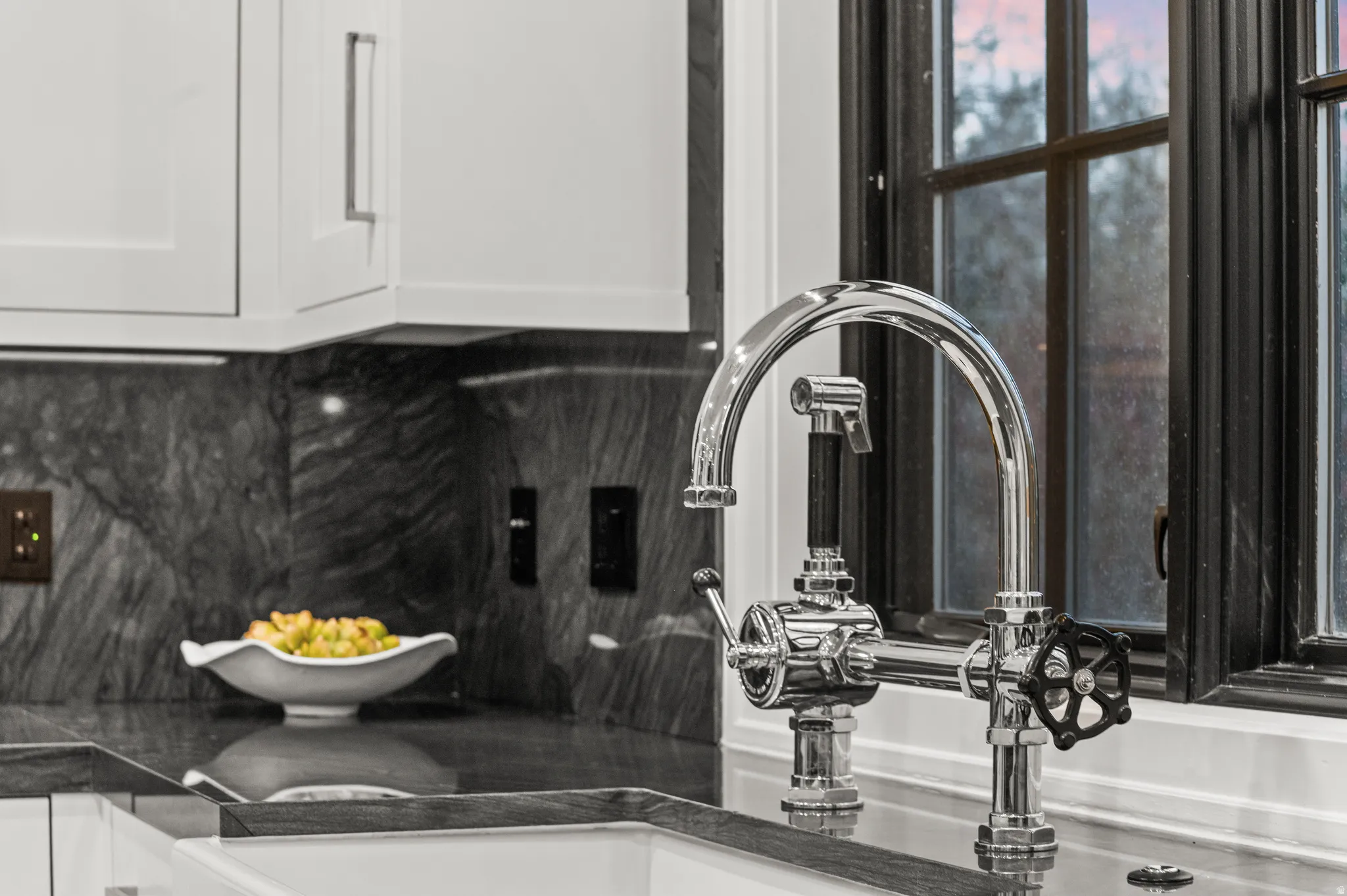 Kitchen view of tasteful backsplash, white cabinets, and dark stone counters