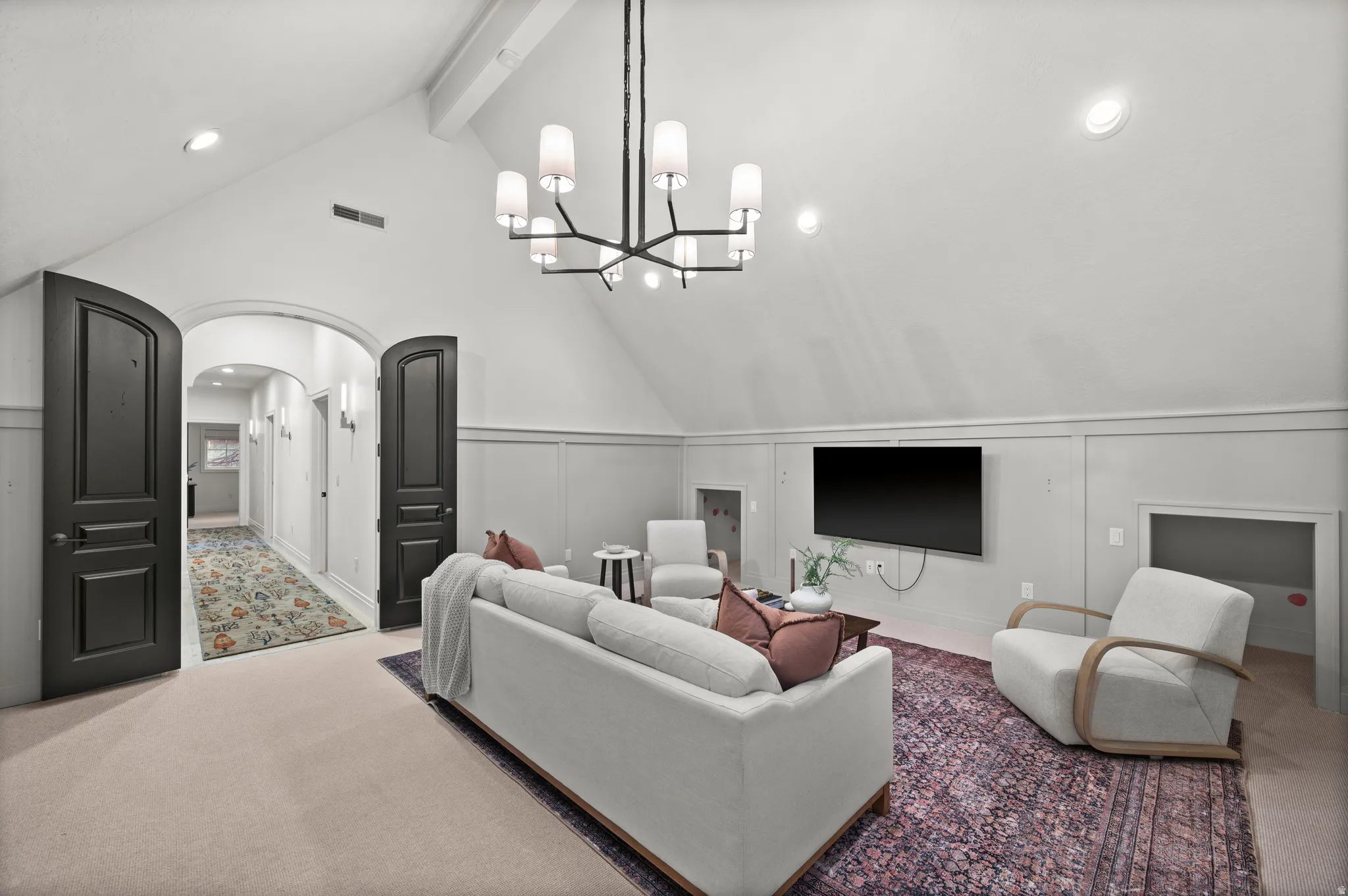 Living area featuring carpet flooring, a decorative wall, recessed lighting, arched walkways, and a chandelier