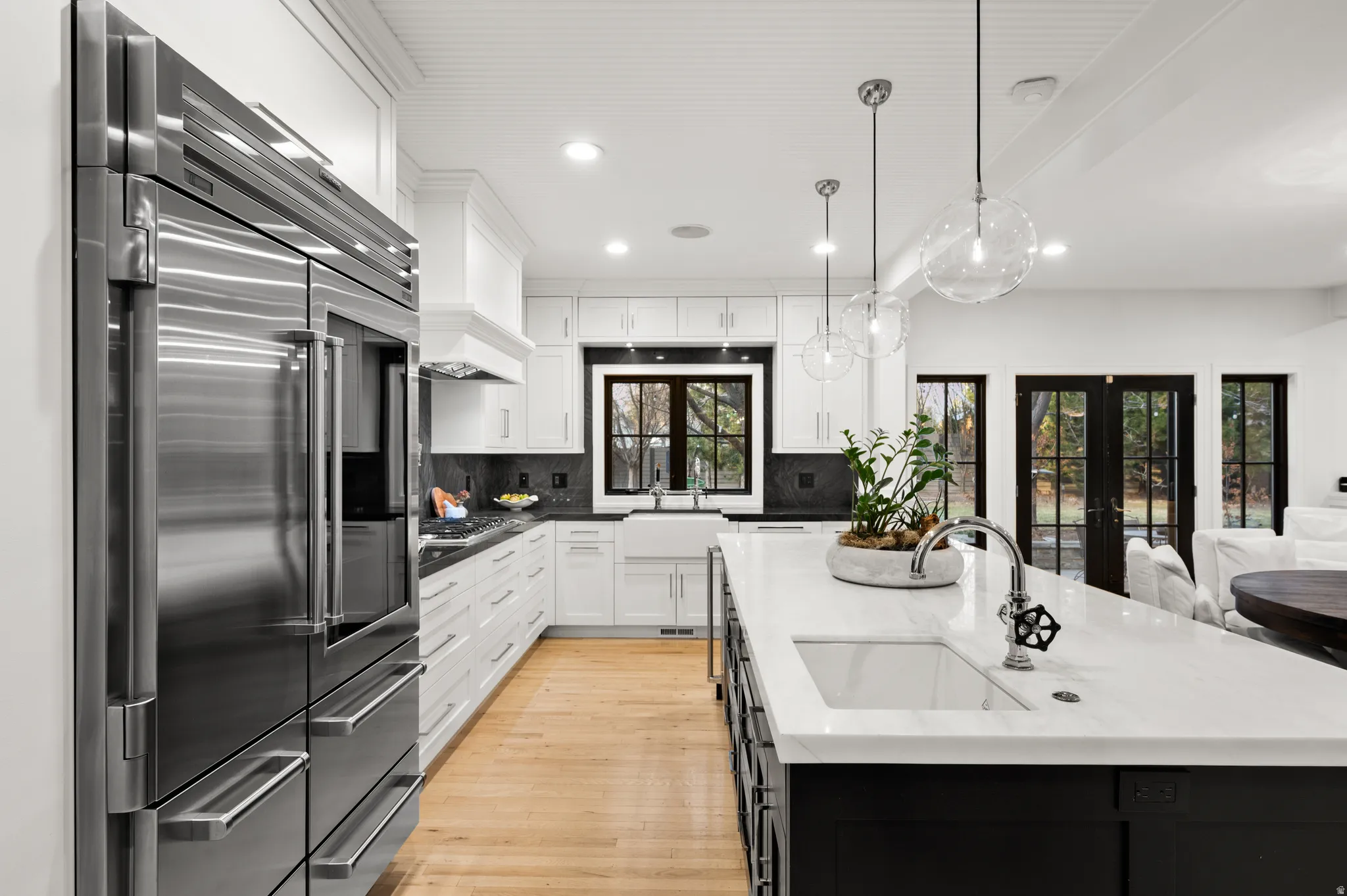 Kitchen with dark cabinetry, french doors, appliances with stainless steel finishes, decorative light fixtures, and decorative backsplash