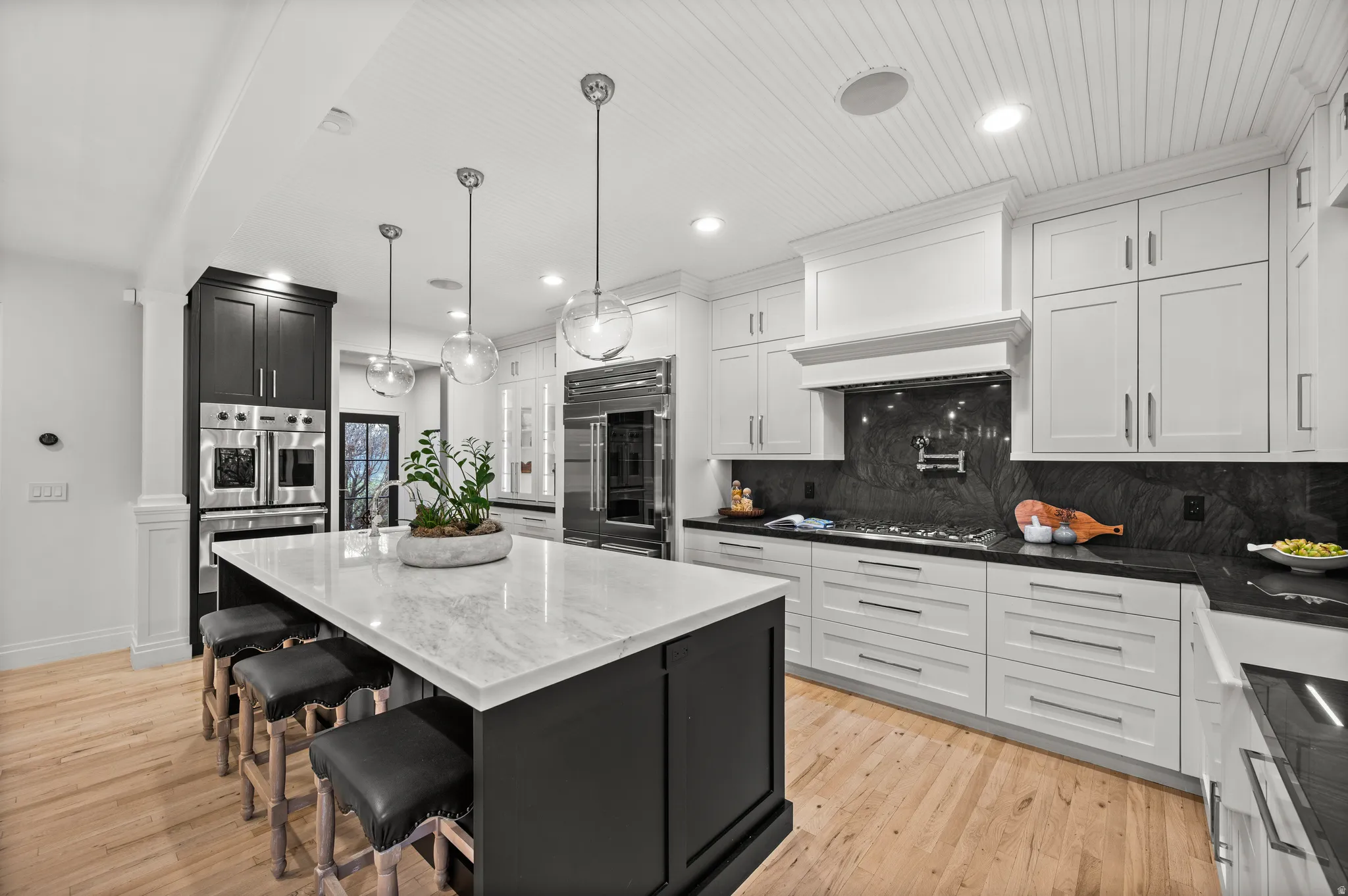 Kitchen with dark cabinetry, a breakfast bar area, dark stone countertops, recessed lighting, and hanging light fixtures