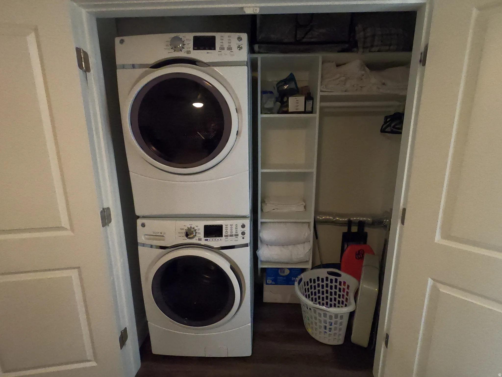 Laundry room featuring stacked washer / dryer and dark wood-type flooring