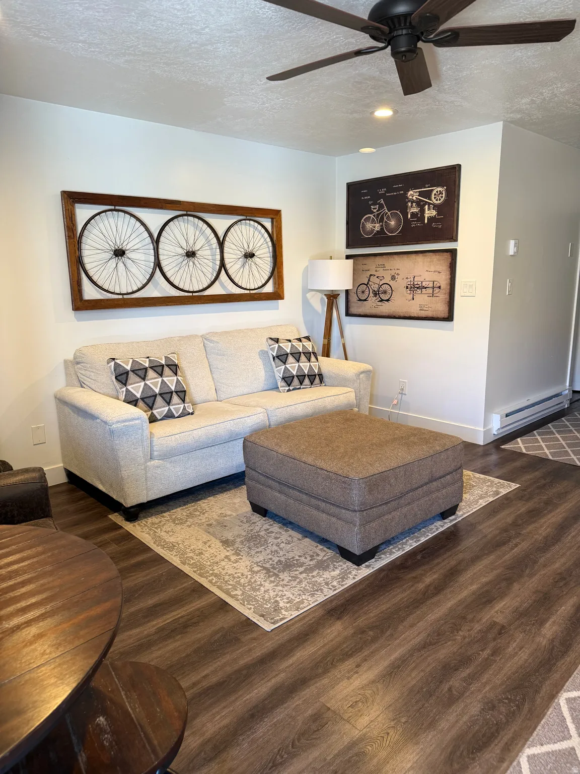 Living room featuring a textured ceiling, baseboard heating, dark wood-type flooring, and ceiling fan